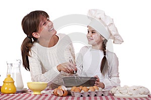 Happy mother with little daughter joyful cooking