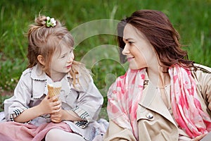 Happy Mother and little Daughter outdoor portrait. Mom and her child enjoying nature together in green park, kissing and hugging,