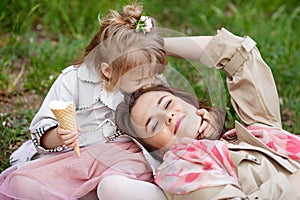 Happy Mother and little Daughter outdoor portrait. Mom and her child enjoying nature together in green park, kissing and hugging,