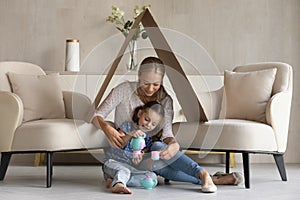 Happy mother with little daughter playing tea party at home