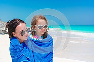 Happy mother and little girl on the beach vacation. Family in towel on the seashore