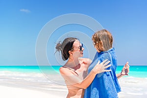 Happy mother and little girl on the beach vacation. Little in towel on the seashore