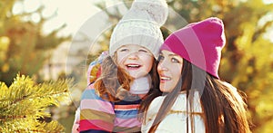 Happy mother and little girl child playing in winter over a snowy background