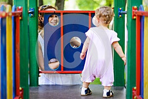 Happy mother looking at her baby girl on the playground