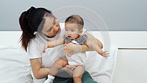 Happy mother playing with baby on bed at home