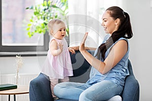 Happy mother playing with baby daughter at home