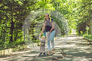 Happy mother playing with baby in the park in autumn. Kid smiling at mum on hands at the park in autumn