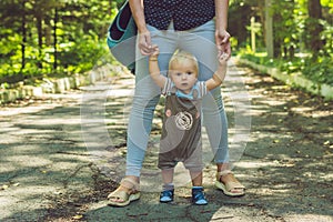 Happy mother playing with baby in the park in autumn. Kid smiling at mum on hands at the park in autumn