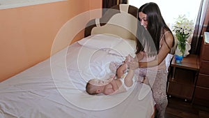 Happy mother playing in bed with newborn baby.