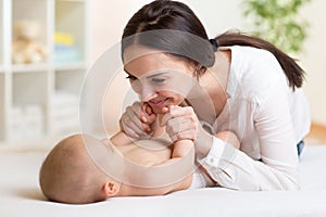Happy mother playing with her baby in bedroom