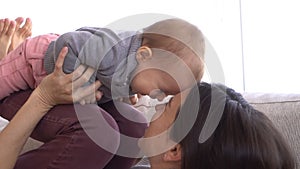 Happy mother playing with her baby daughter at home