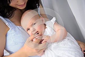 Happy mother playing with her baby girl at home