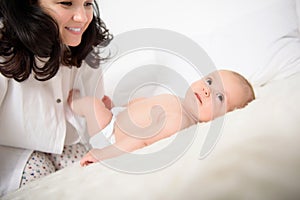 Happy mother playing with her baby girl at home