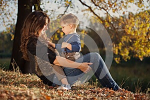 Happy mother playing with her son outdoor in autumn
