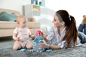 Happy mother playing with little baby on floor