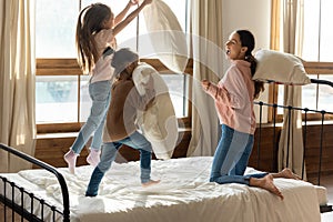 Happy mother playing pillow fight with two little daughters