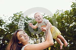 A happy mother is playing with a toddler in the park.