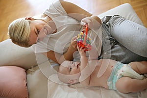 Happy mother plying with her little baby boy at home photo