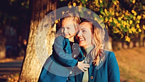 Happy mother and pretty daughter hugging outdoors. Happy family time on a walk in autumn park. Autumn fashion, lifestyle