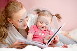 Happy mother read a book to baby girl