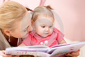 Happy mother read book to baby girl indoors