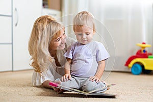 Happy mother read a book to child boy indoors