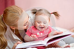 Happy mother read a book to child girl