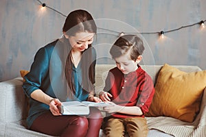 Happy mother reading book to child son at home, learning toddlers to read,