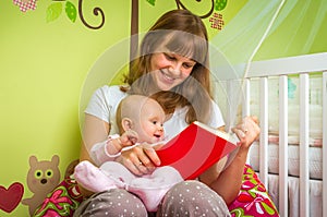 Happy mother reading a book to her baby girl
