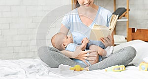 Happy mother reading book to her toddler at home