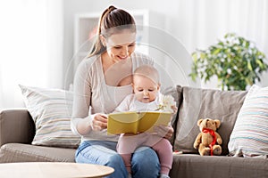 happy mother reading book to little baby at home