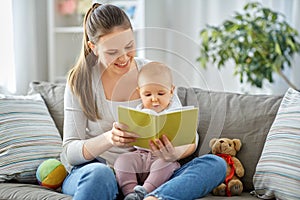 happy mother reading book to little baby at home