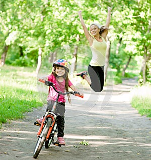 Happy mother rejoices that her daughter learned to ride a bike