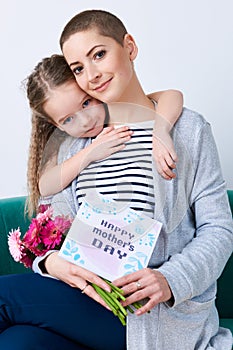 Happy Mother`s Day background. Cute little girl hugging mom after giving her mothers day card.