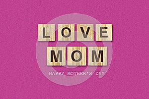 Happy Mother`s Day background. Inscription, Love Mom, on wooden blocks. Pink background. Congratulatory background