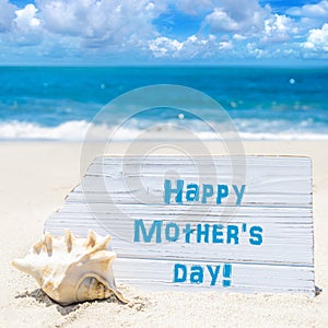 Happy mother`s day background with seashell on the sandy beach