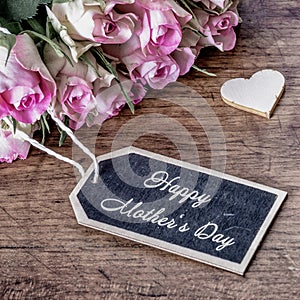 Happy Mother`s Day background vintage - Bouquet of pink roses on rustic wooden table and two wooden hearts, with space for text