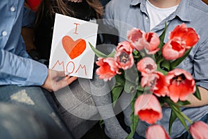 Happy mother`s day card made by a child with flowers. Cropped photo of greeting woman with Mother`s day