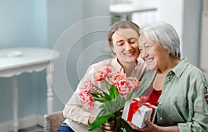 Happy Mother's Day. The child daughter congratulates her mother and gives her a homemade card and flowers pink