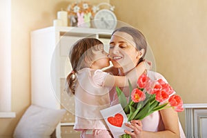 Happy Mother`s Day. The child daughter congratulates her mother and gives her a homemade card and flowers pink tulips