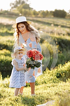 Happy mother`s day. Child daughter congratulates mom and gives her a bouquet of flowers outdoors. Mum and girl smiling and huggin