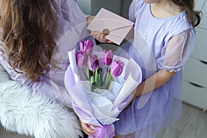Happy mother`s day! Child daughter congratulates mom and gives her flowers tulips