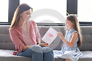 Happy mother`s day! Child daughter congratulates mom and gives her postcard