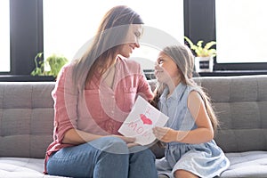 Happy mother`s day! Child daughter congratulates mom and gives her postcard