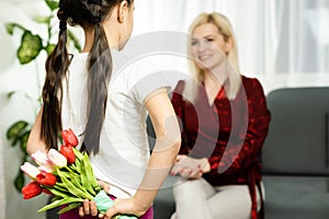 Happy mother& x27;s day. Child daughter congratulates moms and gives her a postcard and flowers tulips