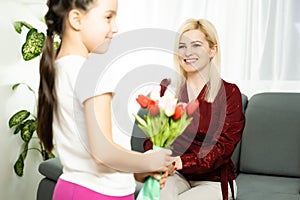 Happy mother& x27;s day. Child daughter congratulates moms and gives her a postcard and flowers tulips