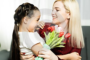 Happy mother& x27;s day. Child daughter congratulates moms and gives her a postcard and flowers tulips