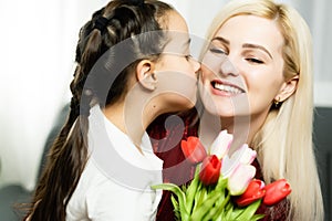 Happy mother's day. Child daughter congratulates moms and gives her a postcard and flowers tulips