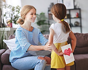 Happy mother`s day! Child daughter congratulates moms and gives her a postcard and yellow flowers tulip