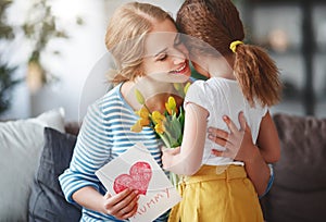 Happy mother`s day! Child daughter congratulates moms and gives her a postcard and yellow flowers tulip